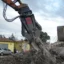 En betongsax på ett skrotupplag klipper spnder betongbalkar.