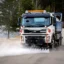 En lastbil med gatutvätt i fronten spolar rent vägar från smuts och damm.