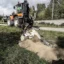 En traktogrävare gräver spår för kabel i diket längs en väg.