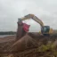 En CAT grävmaskin står på en nyanläggning och siktar anläggningsjord.