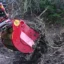 En röd RS8-14 siktskopa som gräver upp jordmassor blandat med lera och trädavfall.