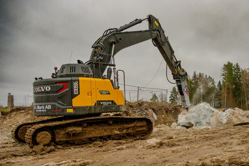Professionell Volvo ECR355EL grävmaskin i arbete på en byggarbetsplats gräver genom robust terräng med sin kraftfulla grävklo Bilden visar maskinens dynamiska kapacitet och tålighet i svåra miljöer perfekt för entreprenörer och byggbranschen som behöver pålitlig tung utrustning Grävmaskinen framhäver Volvos engagemang för hållbarhet och effektivitet i byggsektorn