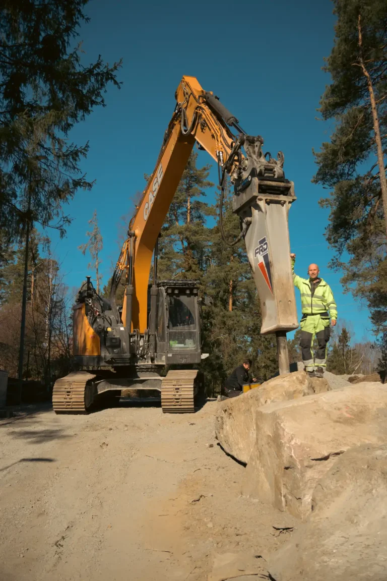 Hööks Grävproduktions grävmaskin med monterad Furukawa FXJ375 hydraulhammare på byggarbetsplats i Sollentuna.