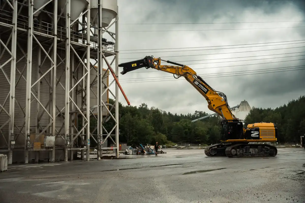 Grävmaskin med VTN stålsax C12500R i arbete vid rivning av industribyggnad.