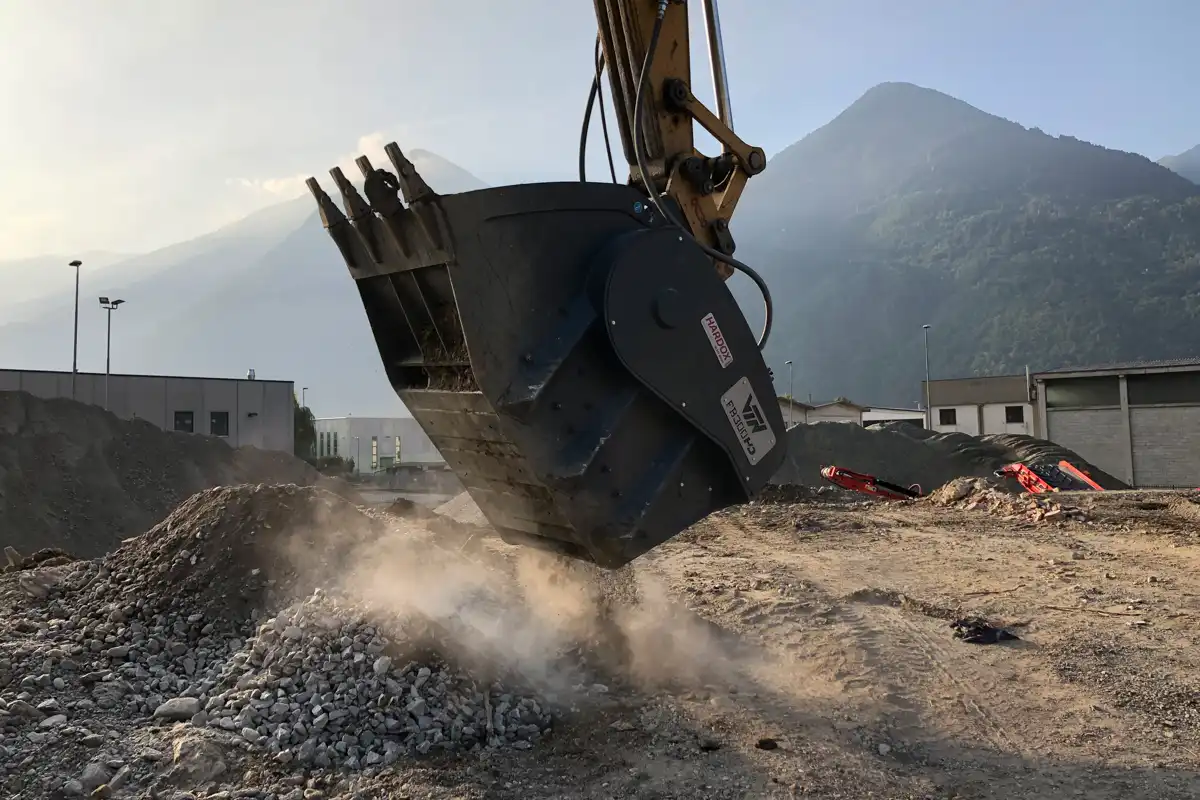 VTN krosskopa i arbete på byggarbetsplats, där betong och sten krossas för återvinning med grävmaskin.