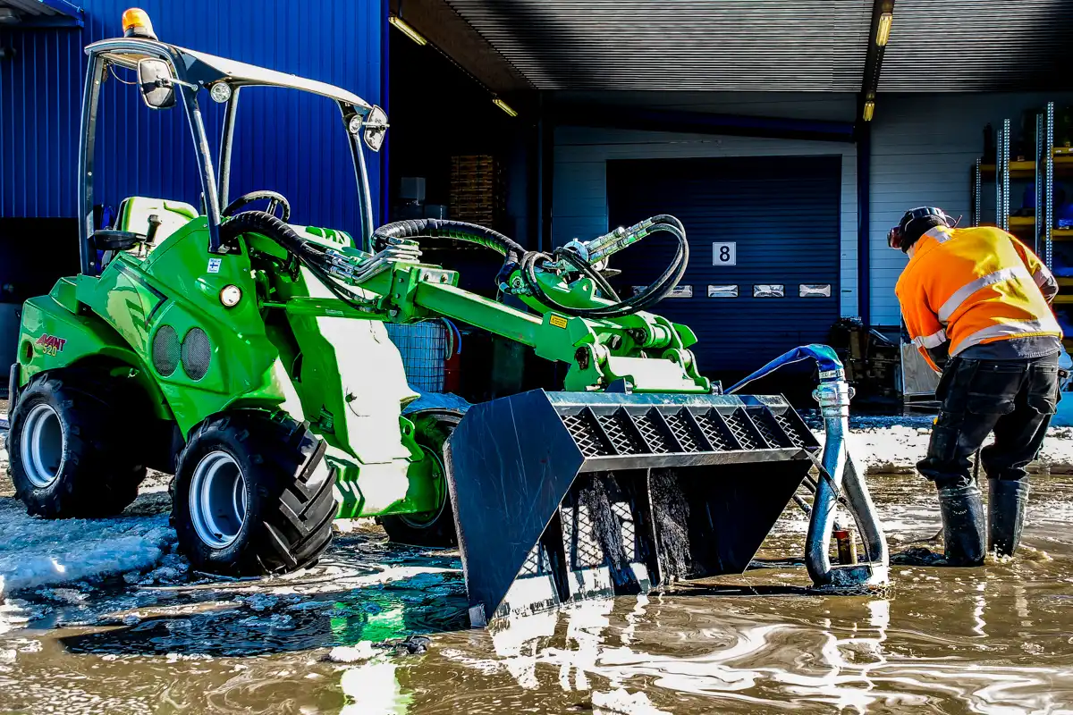 Hydraulisk dränkpump monterad på kompaktlastare för effektiv vattenhantering vid översvämmat arbetsområde