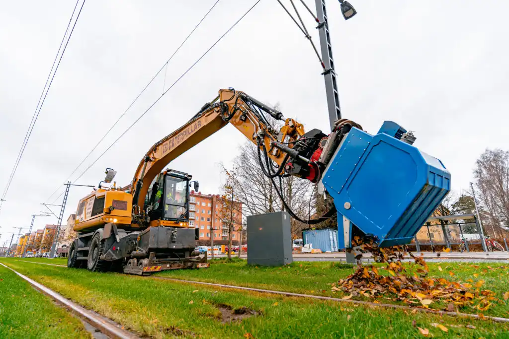 Vakuumskopa monterad på grävmaskin används för att suga upp löv och material vid spårvägsarbete