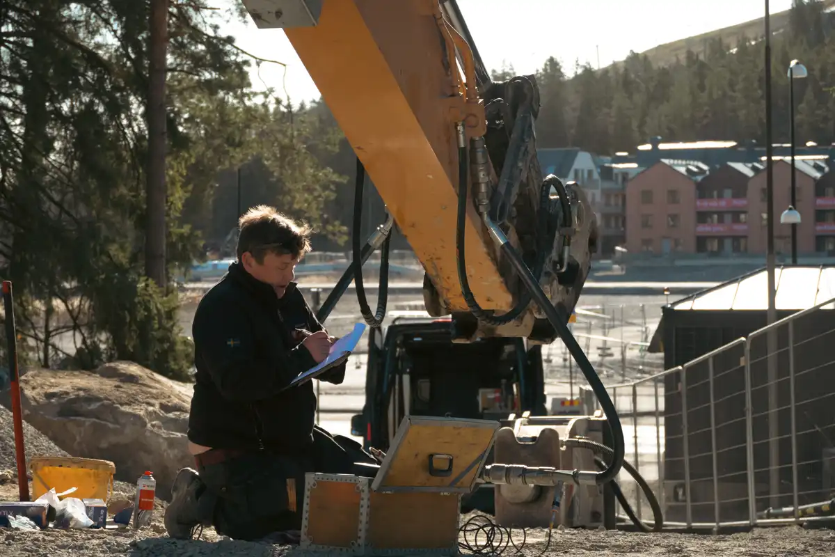 Servicetekniker från AMAS mäter hydraultryck och flöde på grävmaskin vid installation av hydraulhammare.