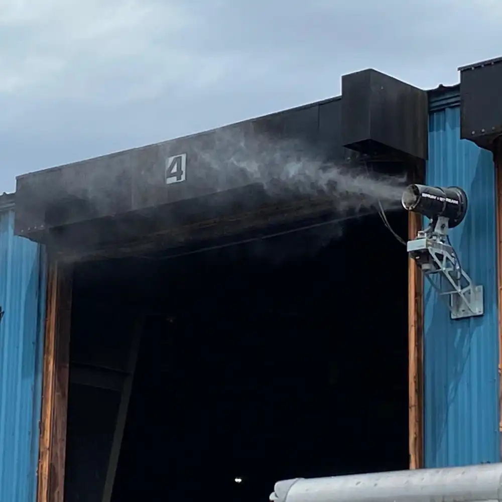 spraystreamminivaggdammbekampningport AMAS Väggmonterad Spraystream Mini sprider vattendimma vid en industriport för att begränsa dammspridning
